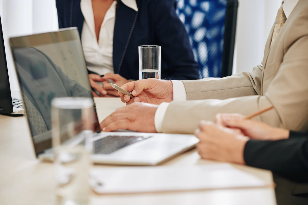 Adults meeting around conference table with laptops