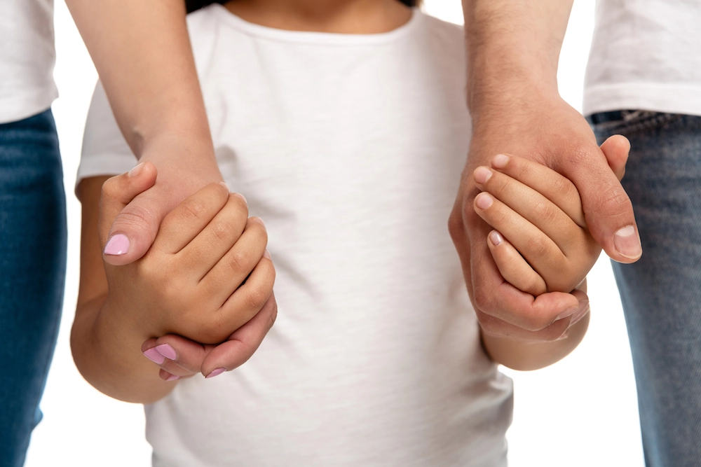 Close-up of child holding hands with a parent on either side